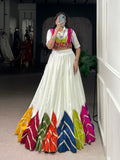 Woman wearing a white rayon lehenga choli with multi-colour patch work and lace details for Navratri.