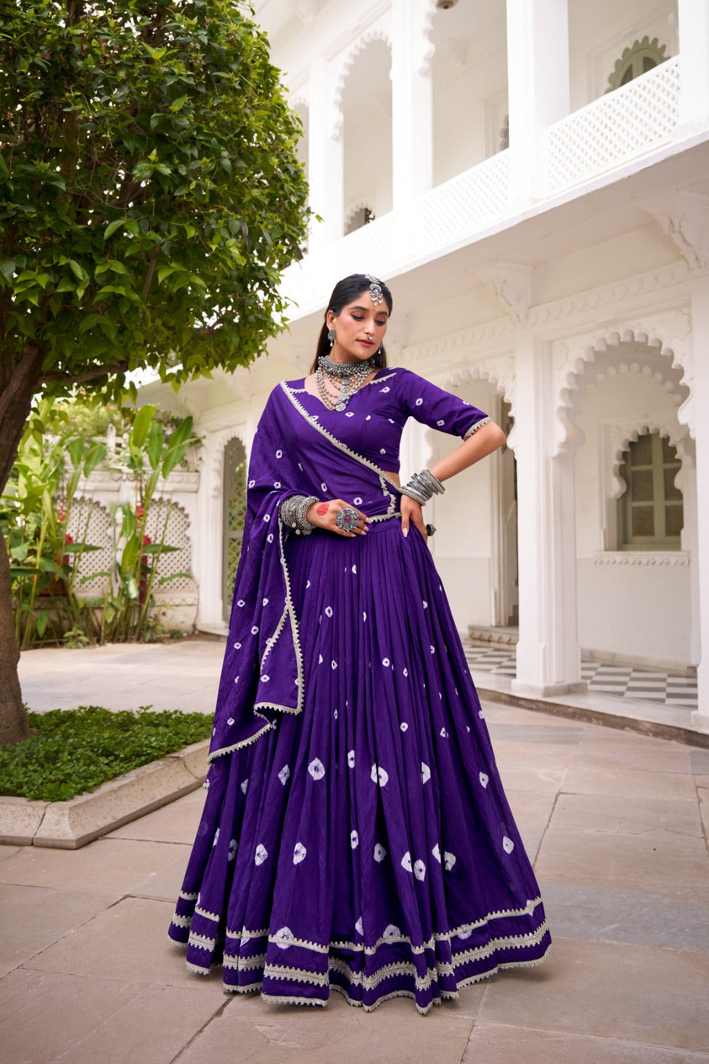 Woman wearing a purple pure Chanderi lehenga choli with Bandhej print and lace trim for festive occasions