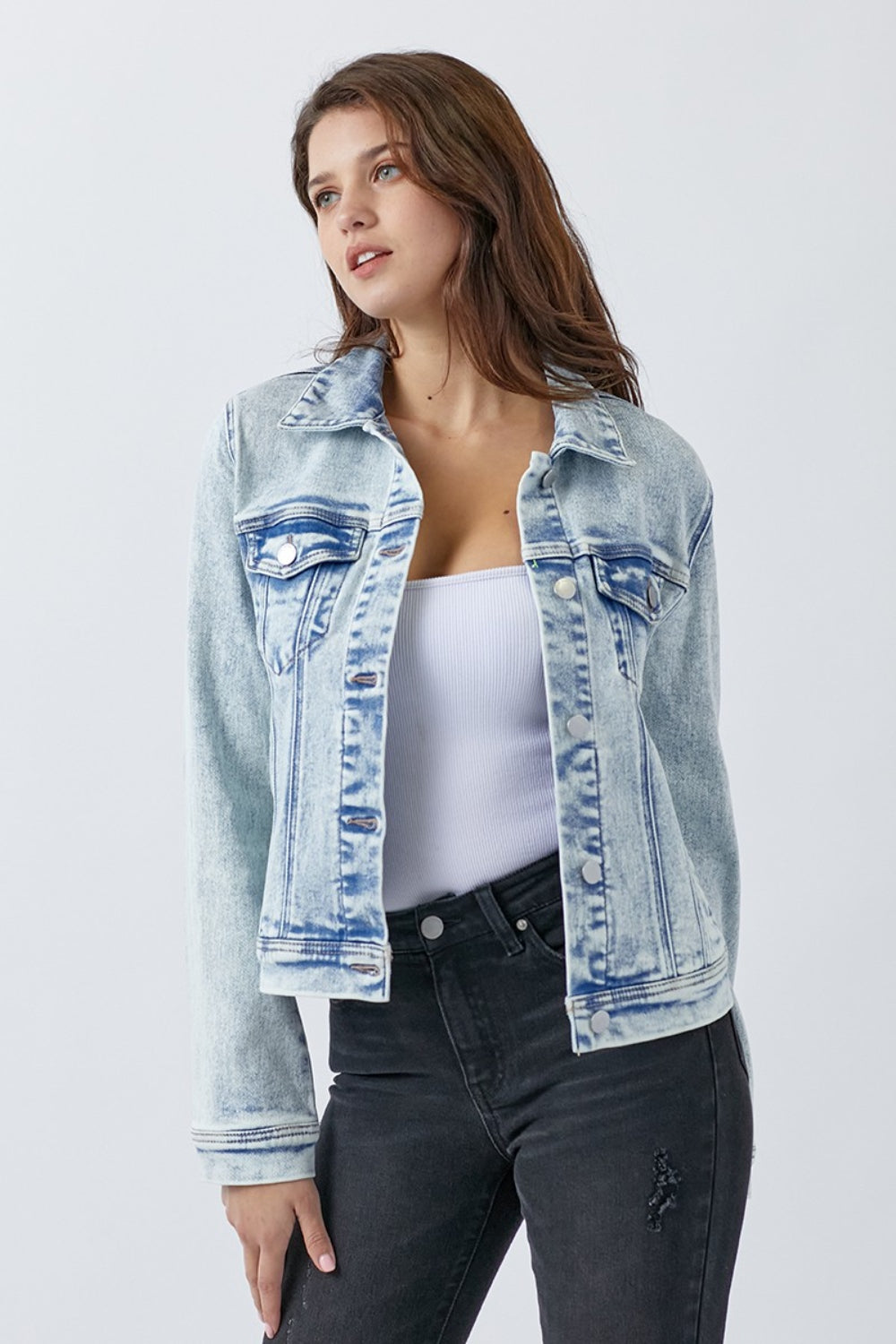 Close up of a blue washed button-up jacket with visible pocket detailing for women.