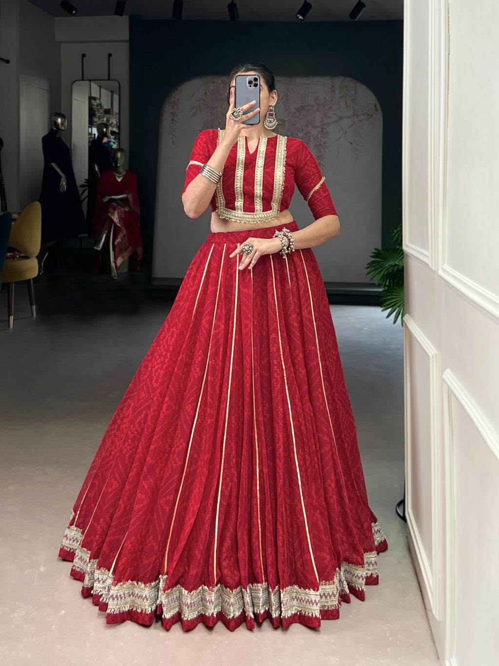 A vibrant red chiffon lehenga choli with traditional Bandhej print, sequin embellishments, and Gotta Patti lace.