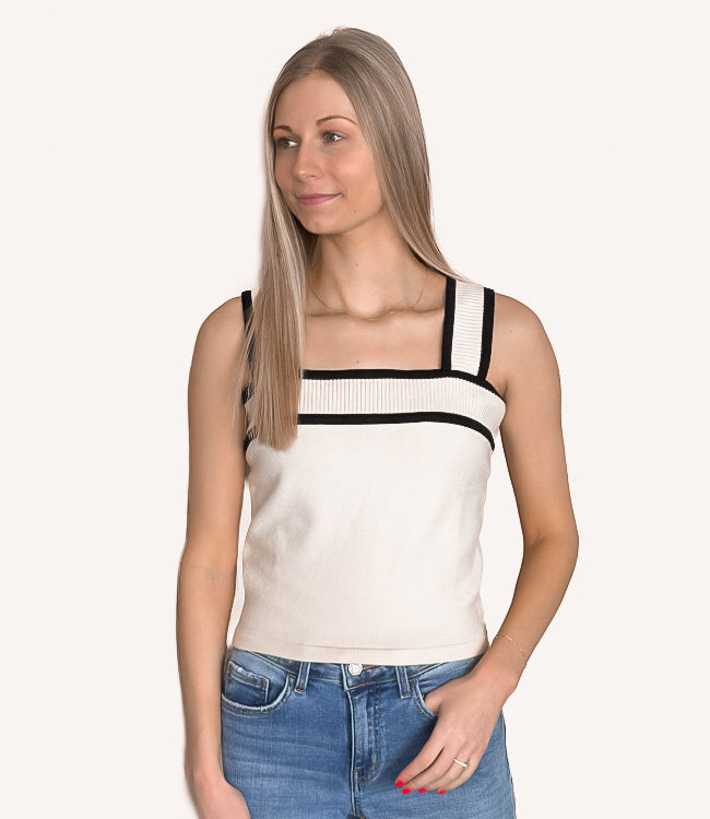 Model wearing a sleeveless contrast sweater tank top in taupe and black colorblock design