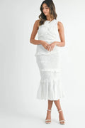 Woman wearing a white cotton popcorn smocked midi dress with ruffled mermaid hemline