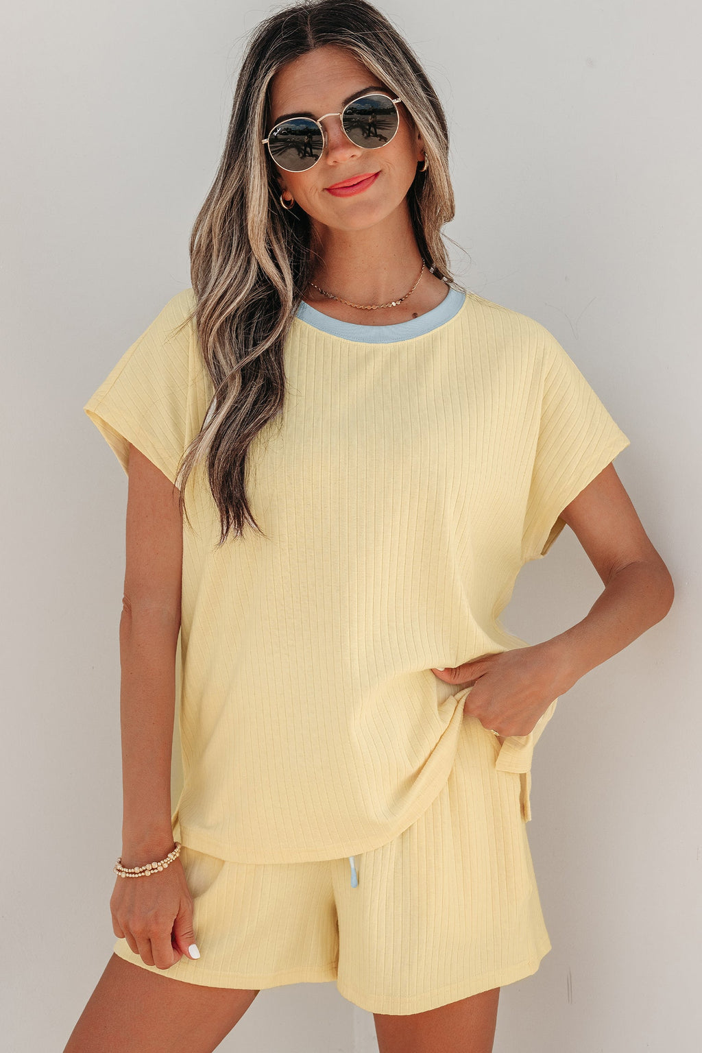 Woman wearing a pastel yellow and light blue ribbed knit short set with contrast trim