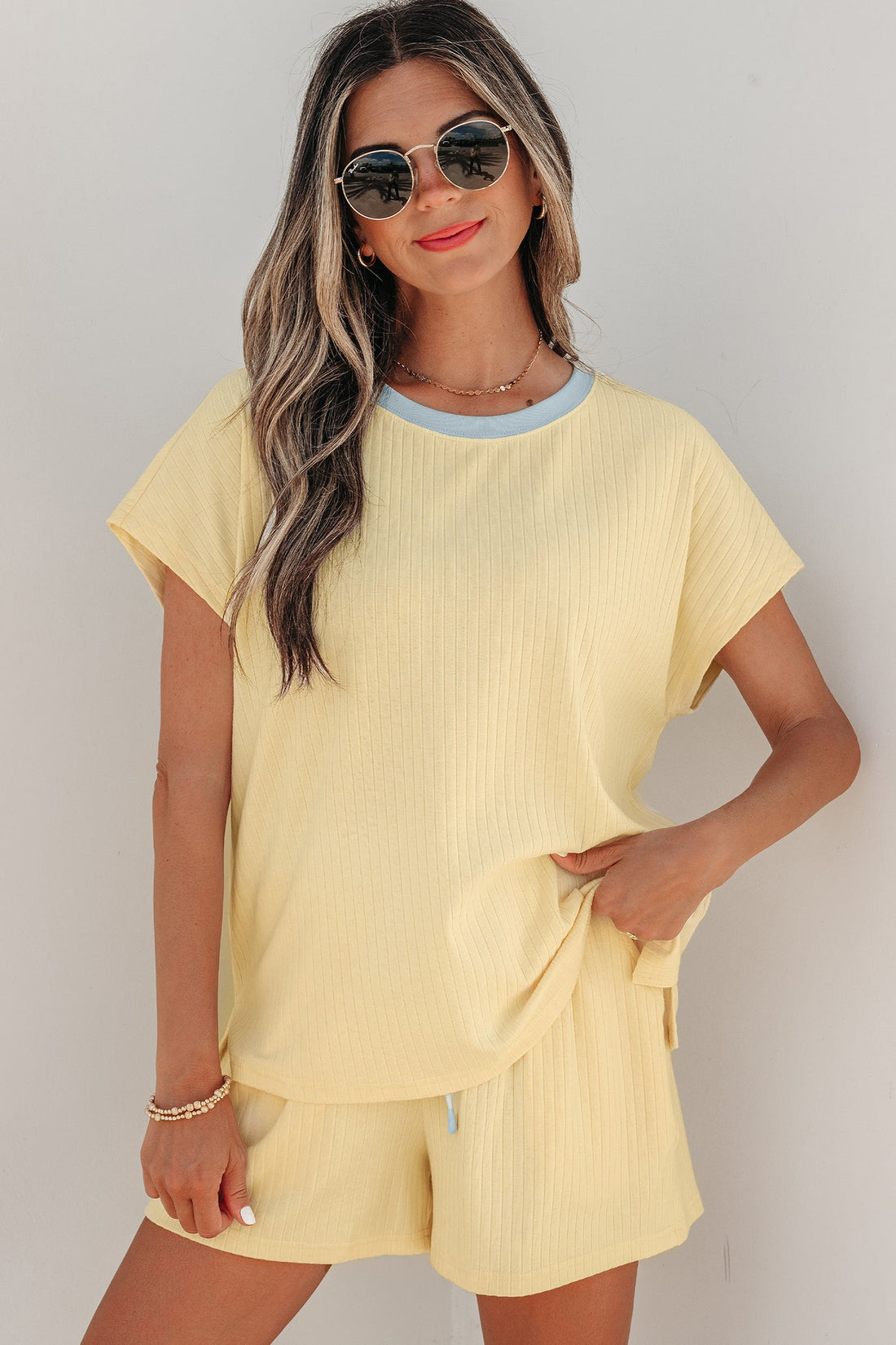 Woman wearing a pastel yellow and light blue ribbed knit short set with contrast trim