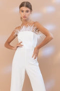 Front view of a white strapless jumpsuit featuring feather accents on the bodice
