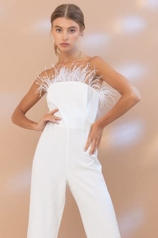 Front view of a white strapless jumpsuit featuring feather accents on the bodice