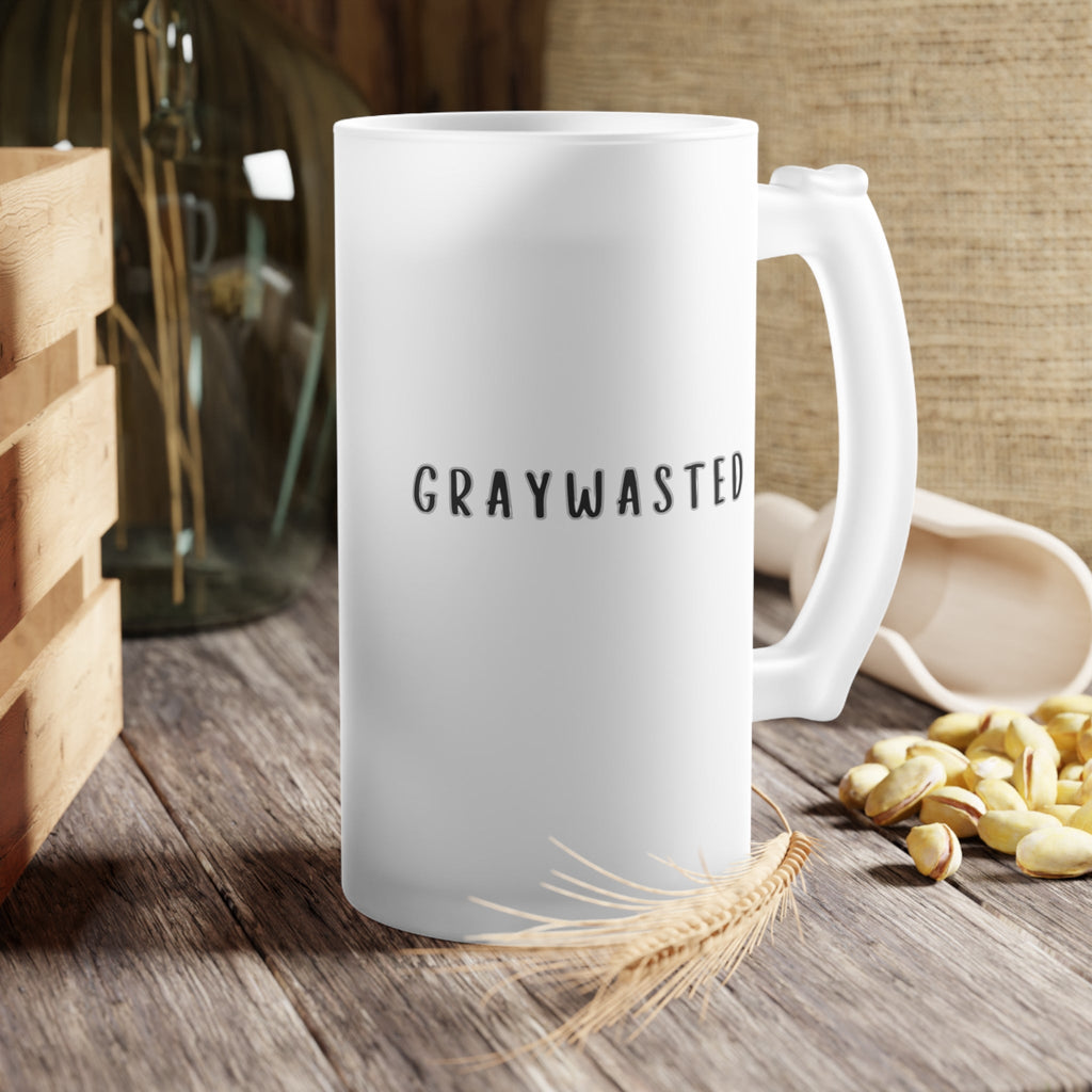 Frosted glass beer mug with black typography sitting on a neutral table surface