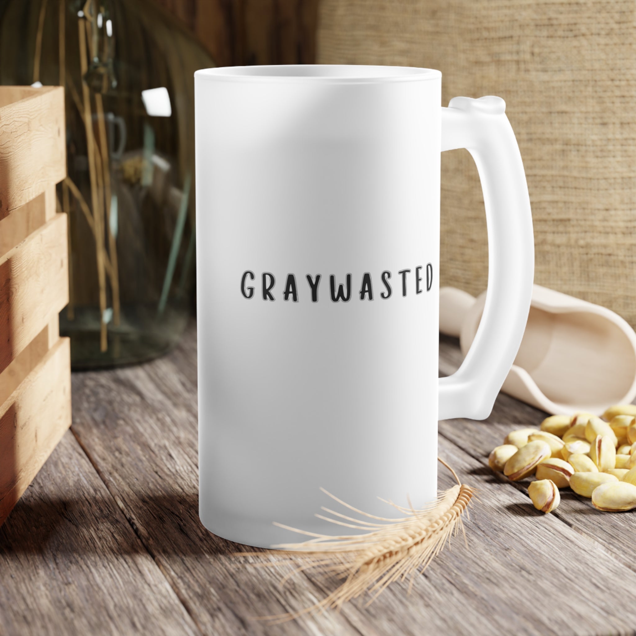 Frosted glass beer mug with black typography sitting on a neutral table surface