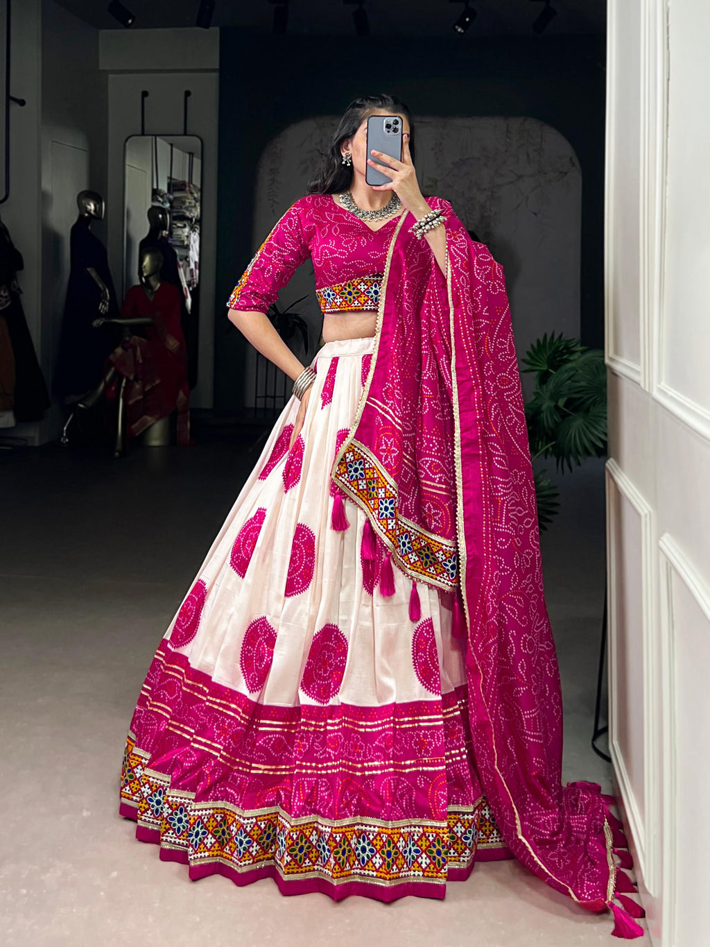 Close up of off-white Tasar silk lehenga with intricate magenta Bandhej pattern and lace trim.