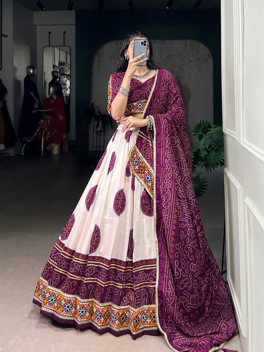 Woman wearing an off-white Tasar silk lehenga with plum-purple Bandhej print and Gamthi work.