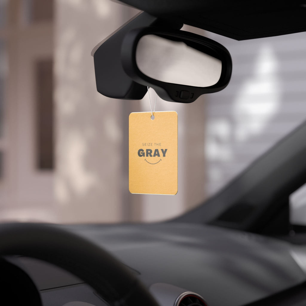 Minimalist mustard yellow and black car air freshener hanging in a modern car interior.