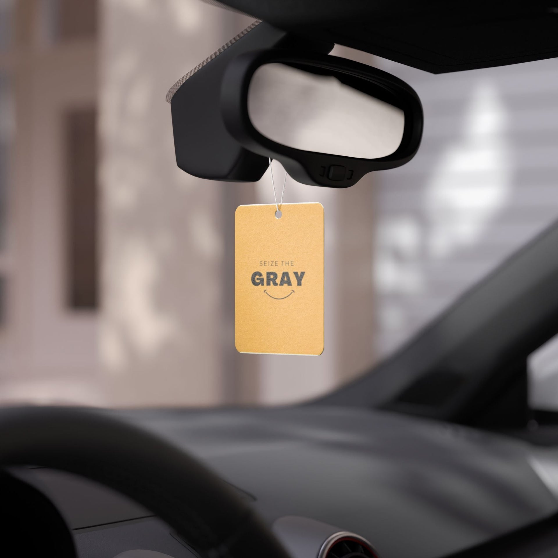 Minimalist mustard yellow and black car air freshener hanging in a modern car interior.