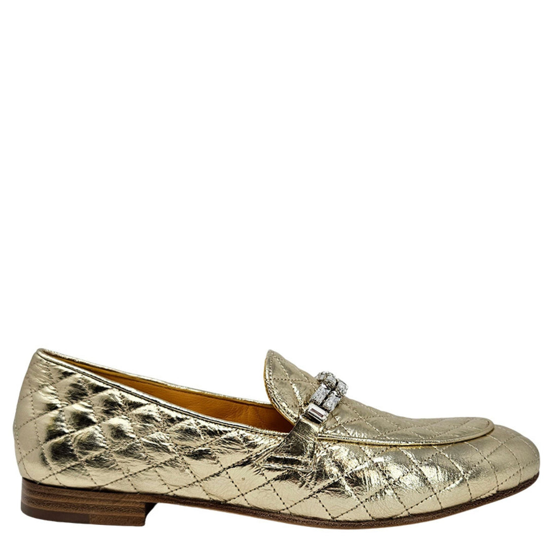 Side profile of a gold quilted leather loafer with a jeweled strap on a white background.