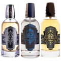 Three glass bottles of 18.21 Man Made cologne in amber and clear liquid with black and silver detailing.
