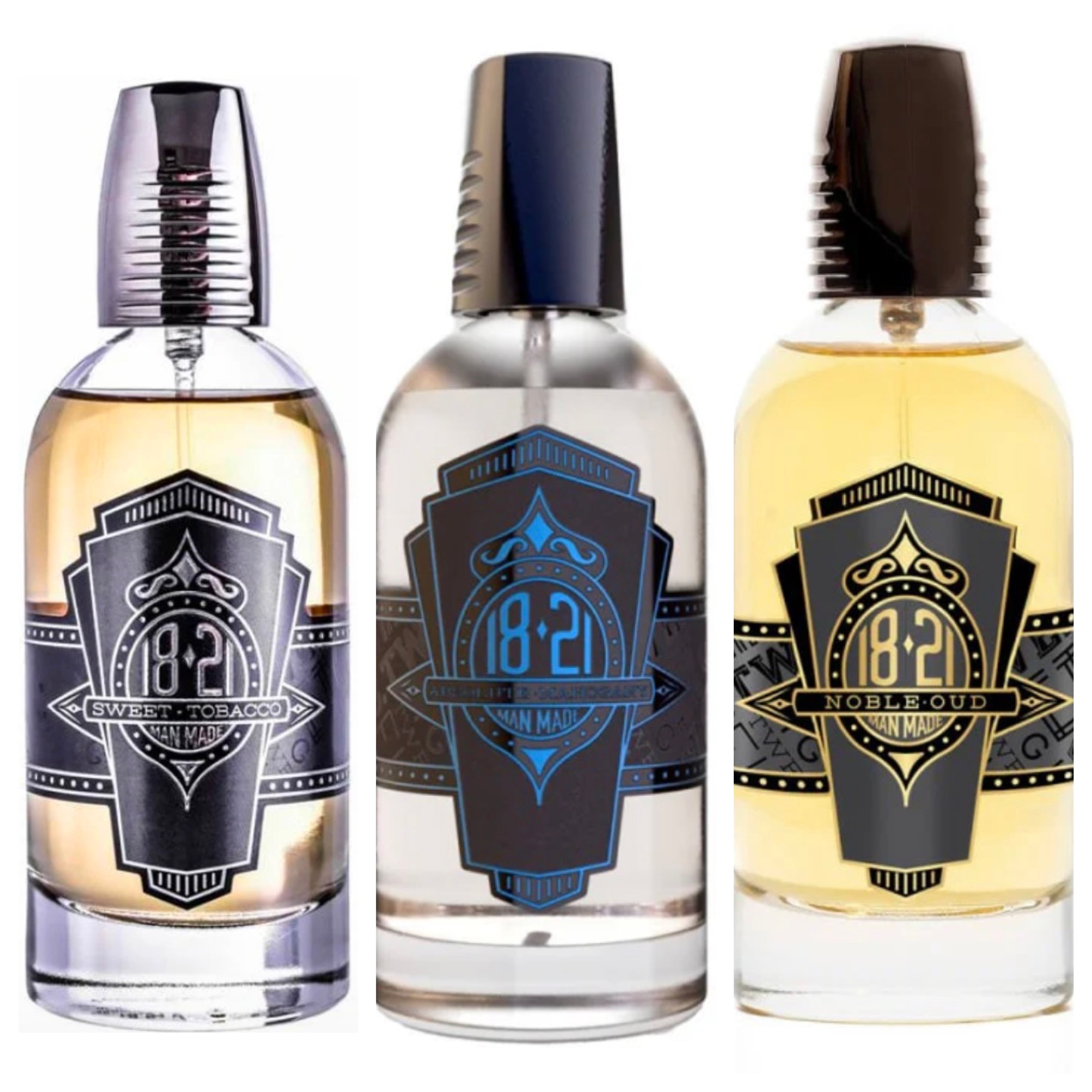 Three glass bottles of 18.21 Man Made cologne in amber and clear liquid with black and silver detailing.