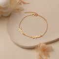 Close-up of a personalized gold-toned name bracelet with a minimalist design on a neutral background.