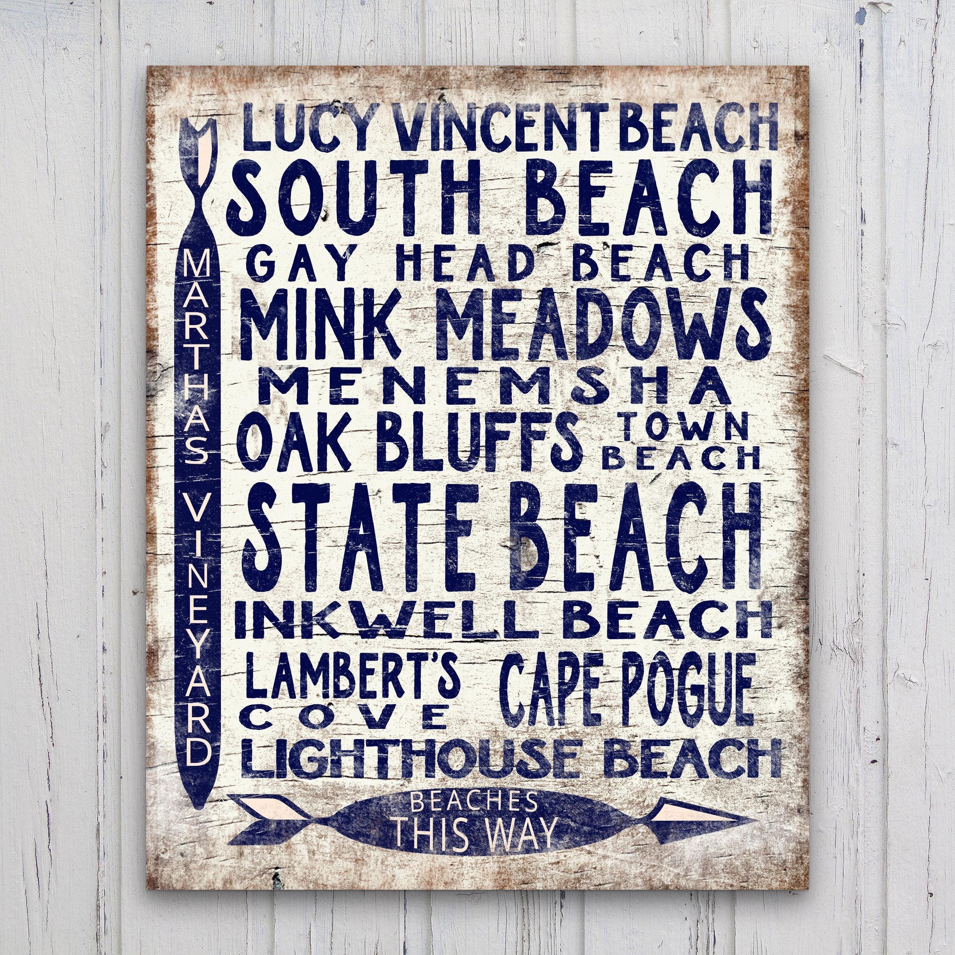 Vintage wood arrow sign featuring Martha's Vineyard beach locations in navy blue on a distressed white background.