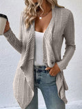 A woman wearing a heather grey, long sleeve, open front, ribbed cardigan over a white top and blue jeans.