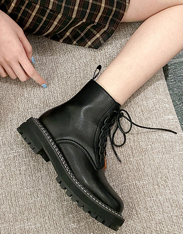 Close-up of Women's Black Lace-Up Ankle Boots with Chunky Lug Sole, styled with a plaid skirt.