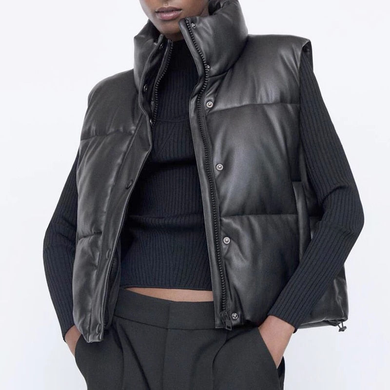 Woman wearing a black faux leather puffer vest with a high collar and full zip closure, styled for a modern Harajuku street look, suitable for layering.
