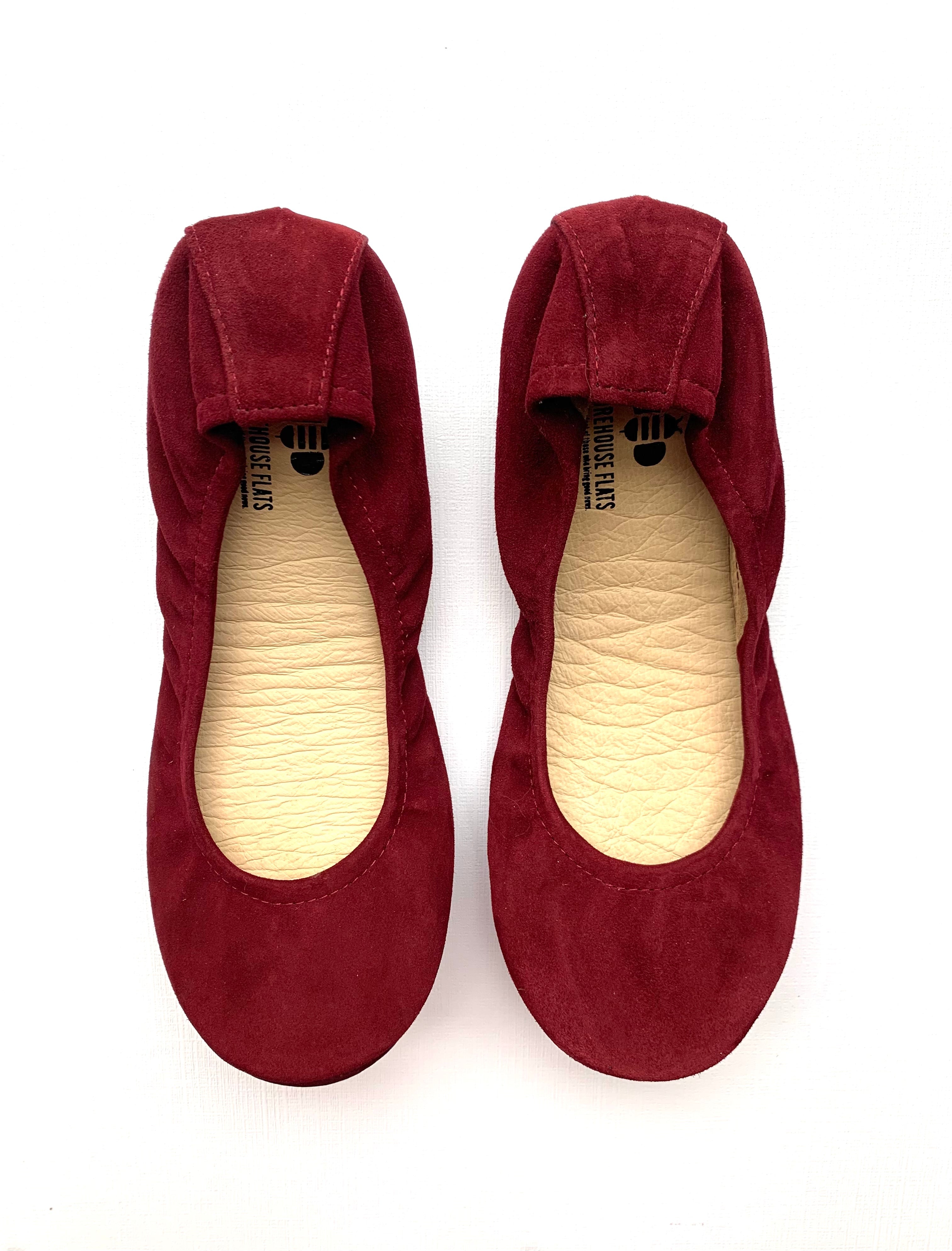 Top-down view of a pair of wine-colored suede ballet flats, followed by a view of the rubberized grip soles featuring The Storehouse Flats logo.