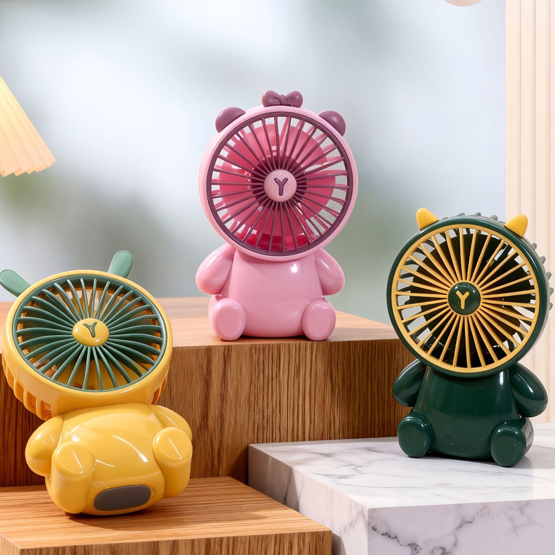 A cute yellow cartoon bear-themed mini desktop fan standing on a wooden table.