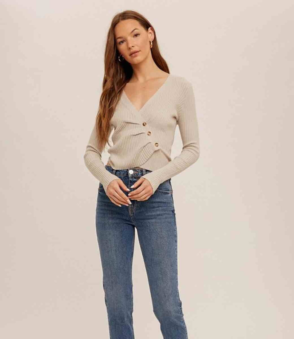 Close-up of the Asymmetrical Pleat Ribbed V-Neck in Dove featuring textured fabric and pleated neckline detail.