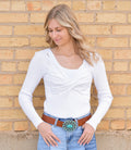 Woman wearing a white cable-knit V-neck sweater with a soft texture.
