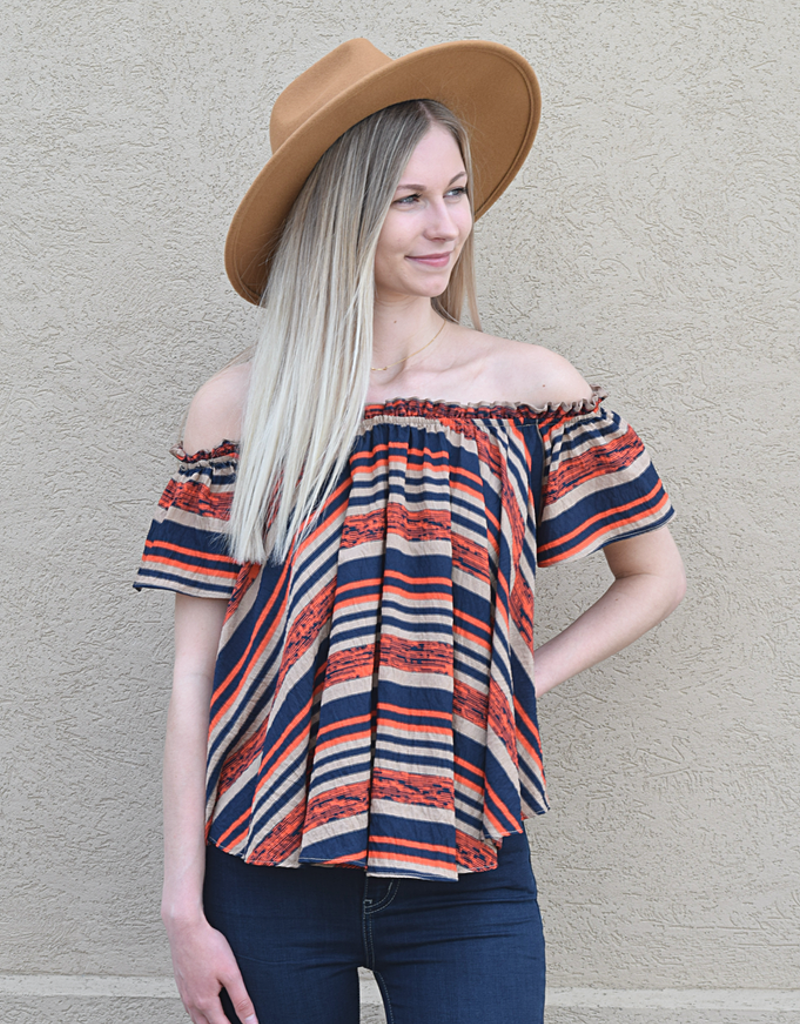 Woman wearing an off-the-shoulder striped woven top in navy blue, burnt orange, and tan colors.
