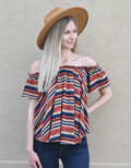 Woman wearing an off-the-shoulder striped woven top in navy blue, burnt orange, and tan colors.