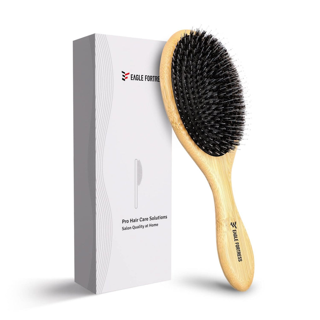 Minimalist bamboo detangler hair brush with light wood handle and black bristles resting on a neutral surface