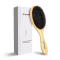Minimalist bamboo detangler hair brush with light wood handle and black bristles resting on a neutral surface
