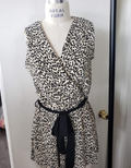 Model wearing a sleeveless cream and black leopard print mini romper with a tie waist and V-neckline.