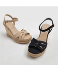 A pair of sleek black strappy wedges by Boutique 23, shown from a side profile view.