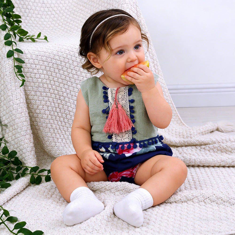 Baby girl wearing a sleeveless floral romper with tassel details and backless design