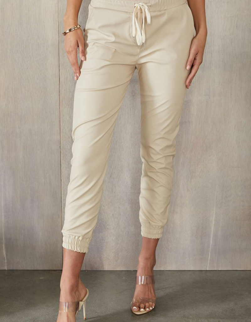 Cream-colored faux leather joggers with a relaxed fit, perfect for casual or dressed-up styling.