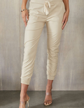 Cream-colored faux leather joggers with a relaxed fit, perfect for casual or dressed-up styling.