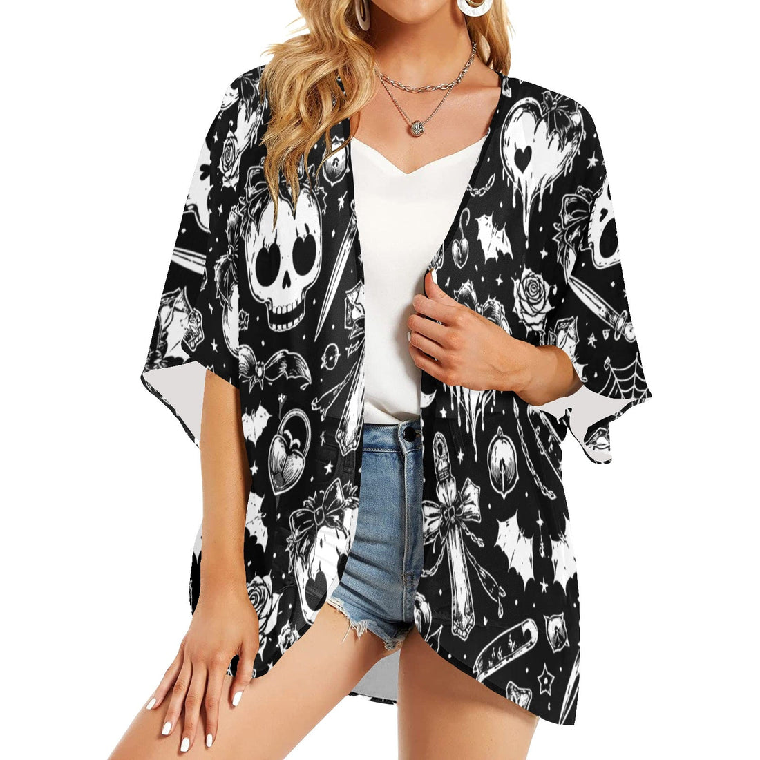 A woman wearing a lightweight black and white chiffon kimono with an all-over skull and gothic pattern, styled open over a white camisole.