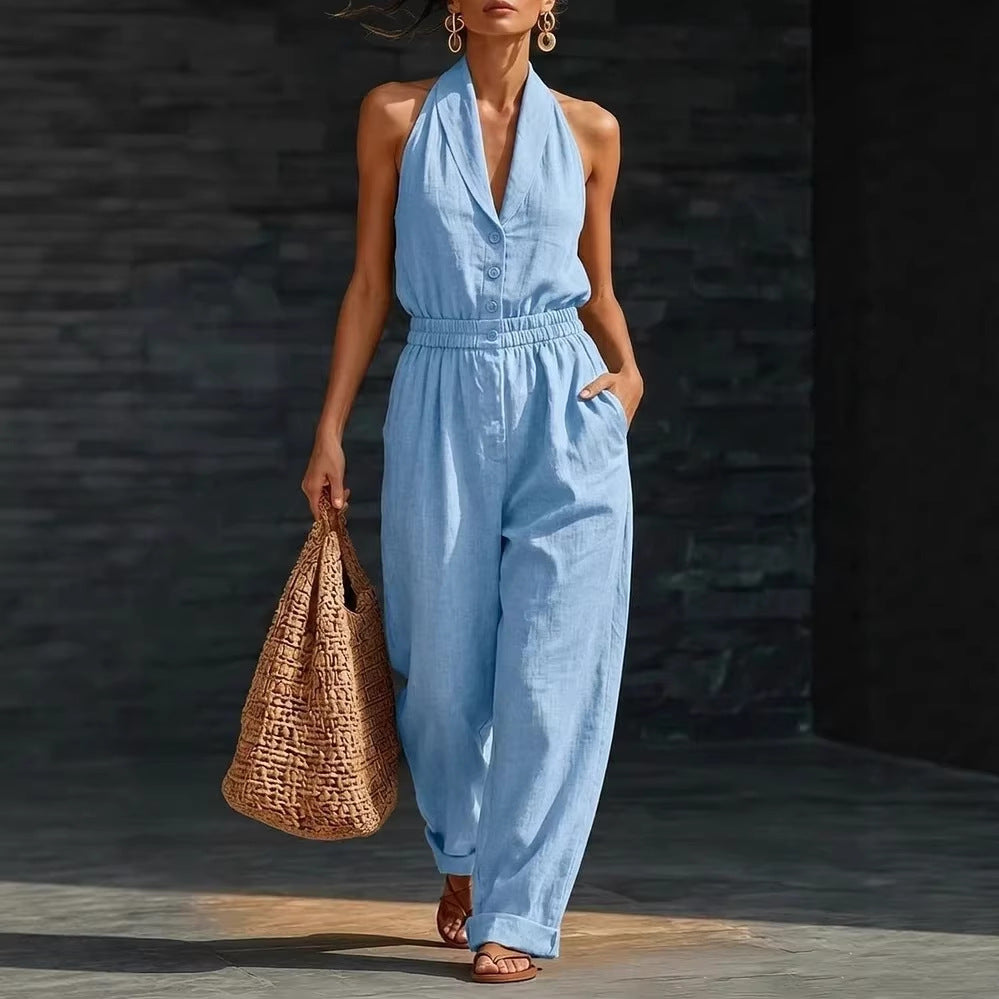 Model wearing a blue V-neck sleeveless button-front jumpsuit with an elastic waist and straight legs.