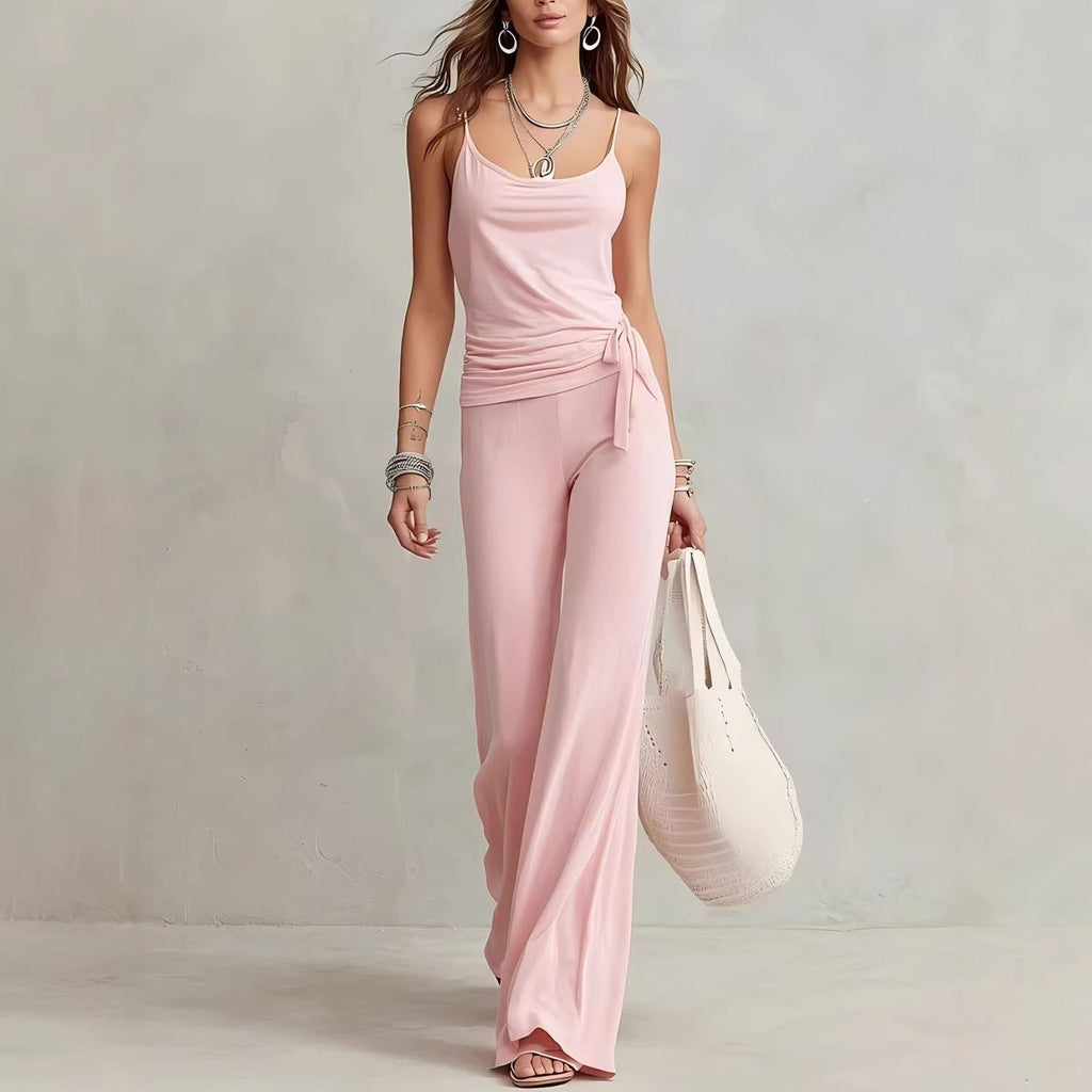 A woman wearing a matching light pink sleeveless top and wide-leg pants set with a tie-waist detail.