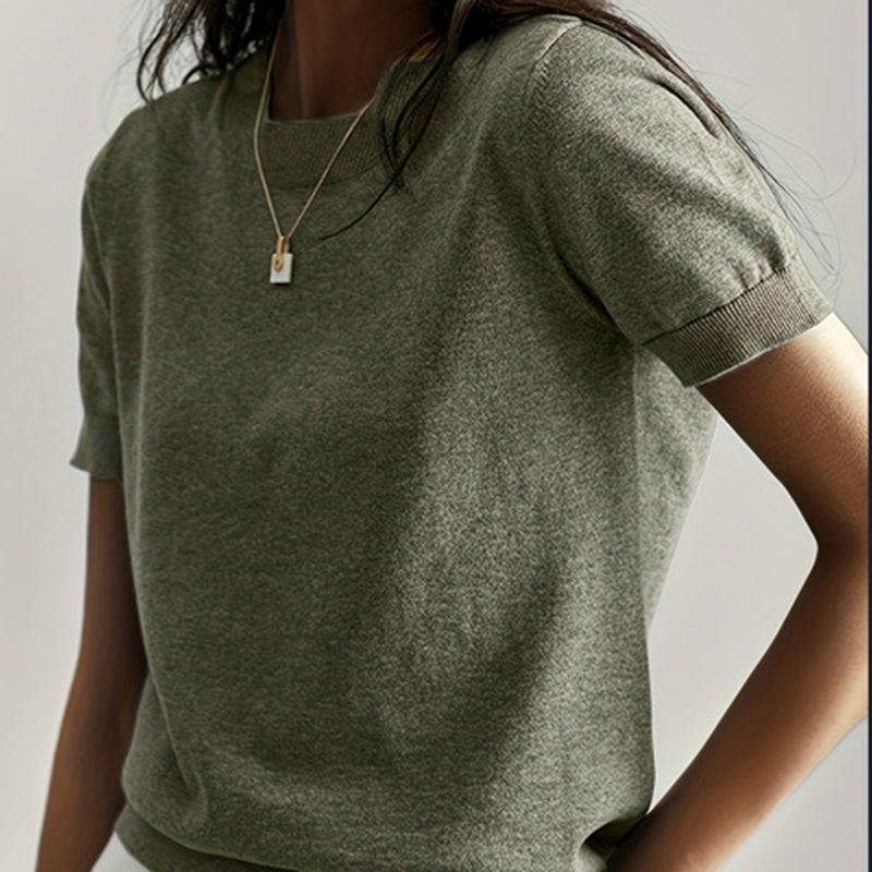 A woman wearing an olive green soft stretch minimalist t-shirt with a slim fit and ribbed cuffs.