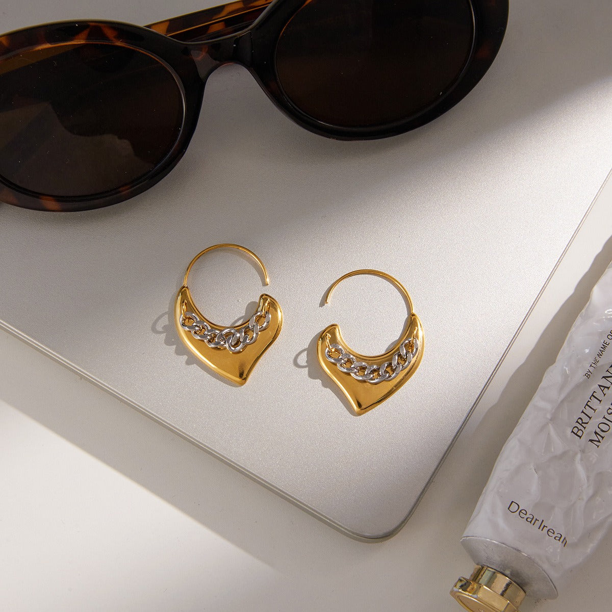 A pair of lightweight 18K gold heart-shaped stud earrings with a polished finish