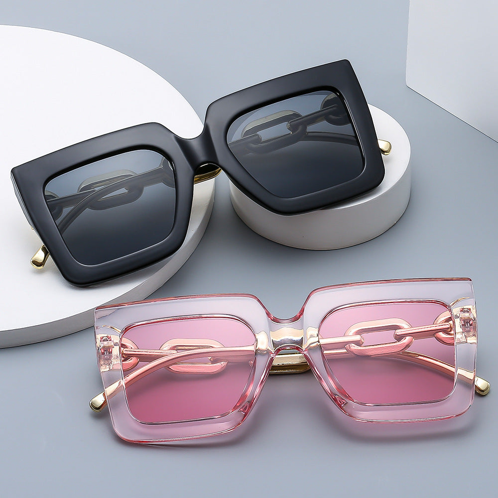 Woman wearing oversized square sunglasses with gold metal chain temple detail