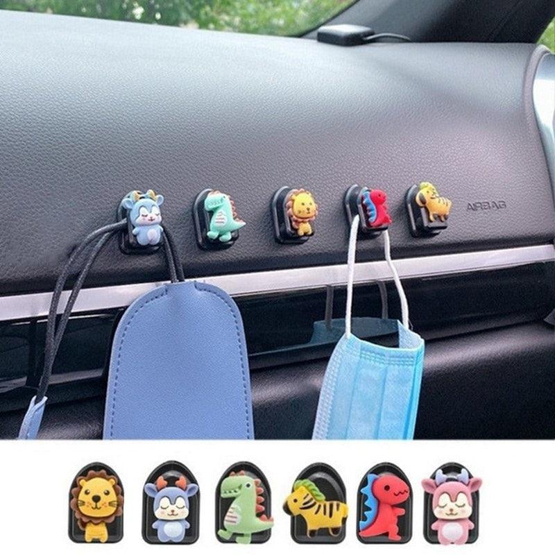 Set of two cute cartoon-themed adhesive car dashboard hooks for organizing small items like masks and hats.