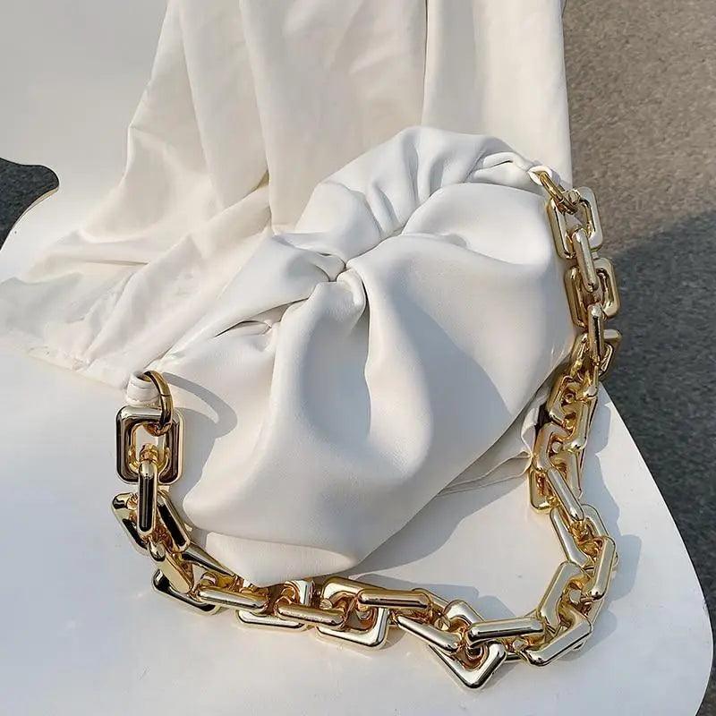 A stylish minimalist women's leather shoulder bag in brown with gold hardware on a neutral background.