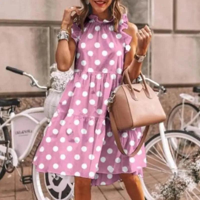 A woman wearing a sleeveless summer dress featuring an all-over polka dot print.