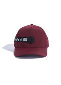 A wine-colored performance baseball cap with a perforated back, rubber logo patch, and branded strap detail.