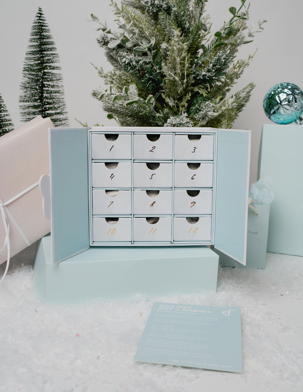12 Days of EF Jewelry Advent Calendar box featuring gold charms and paperclip necklace in pastel blue and white packaging