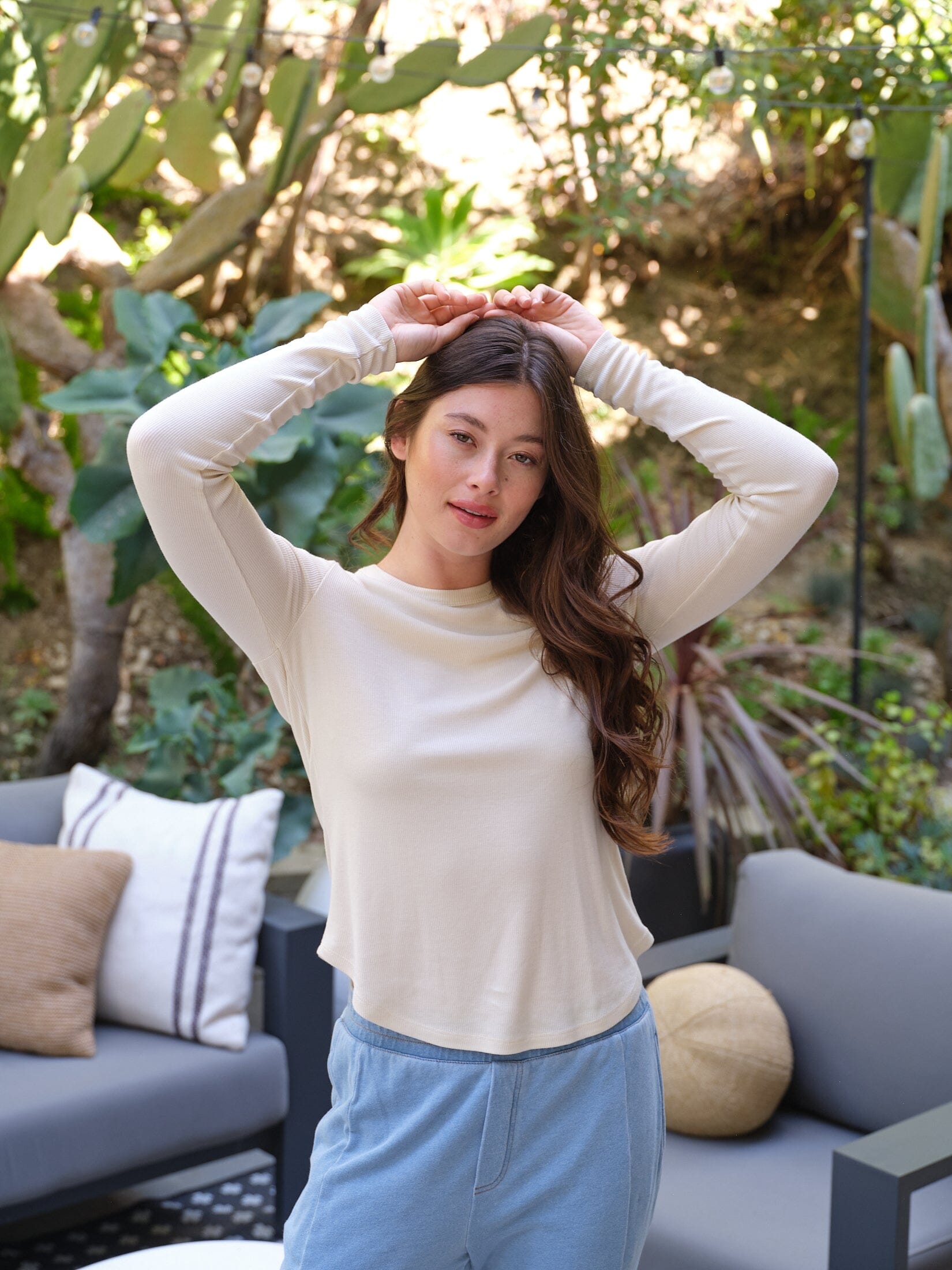 Woman wearing a body-skimming long sleeve off-white Feather Rib crew tee with a curved hem.