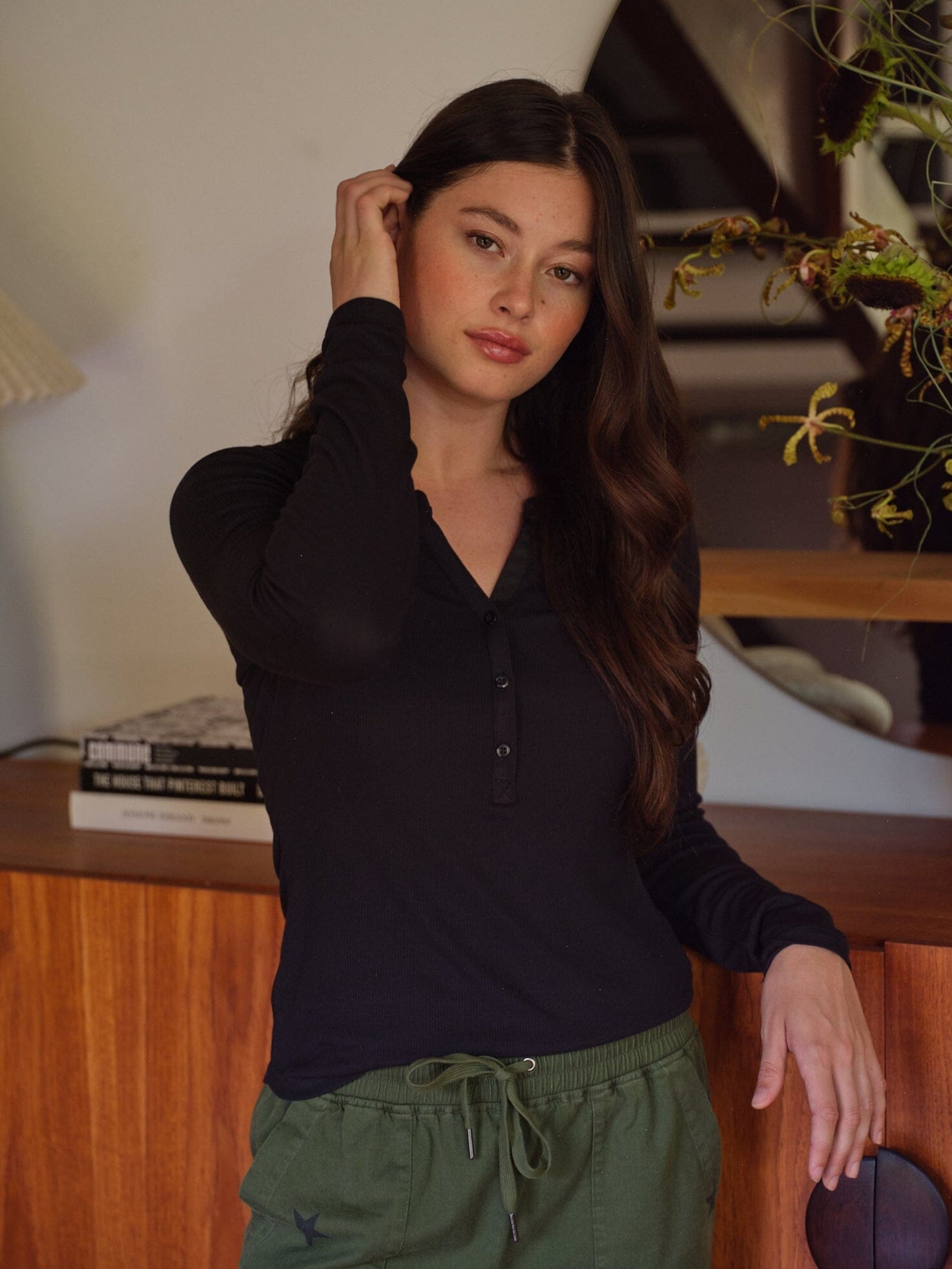 Woman wearing a black long sleeve ribbed knit henley top with functional buttons